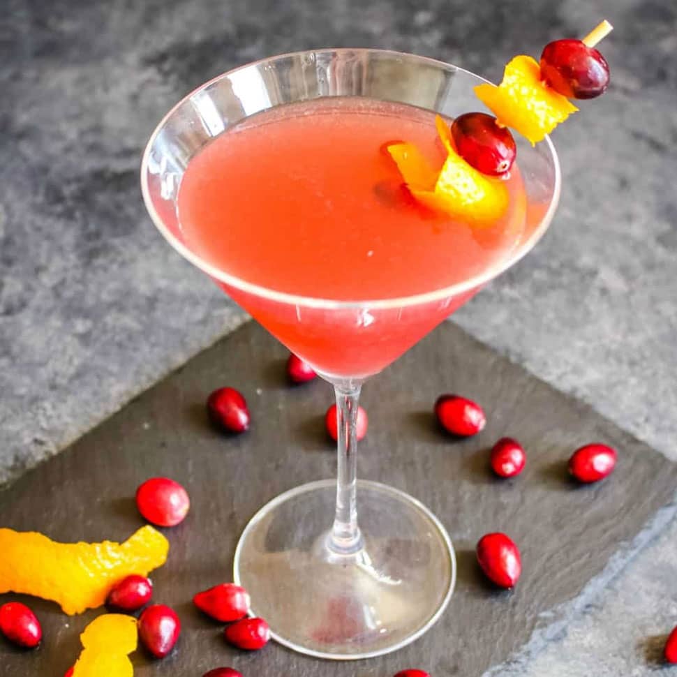un cosmopolitan cocktail dans un joli verre, avec des graines de cranberries en déco