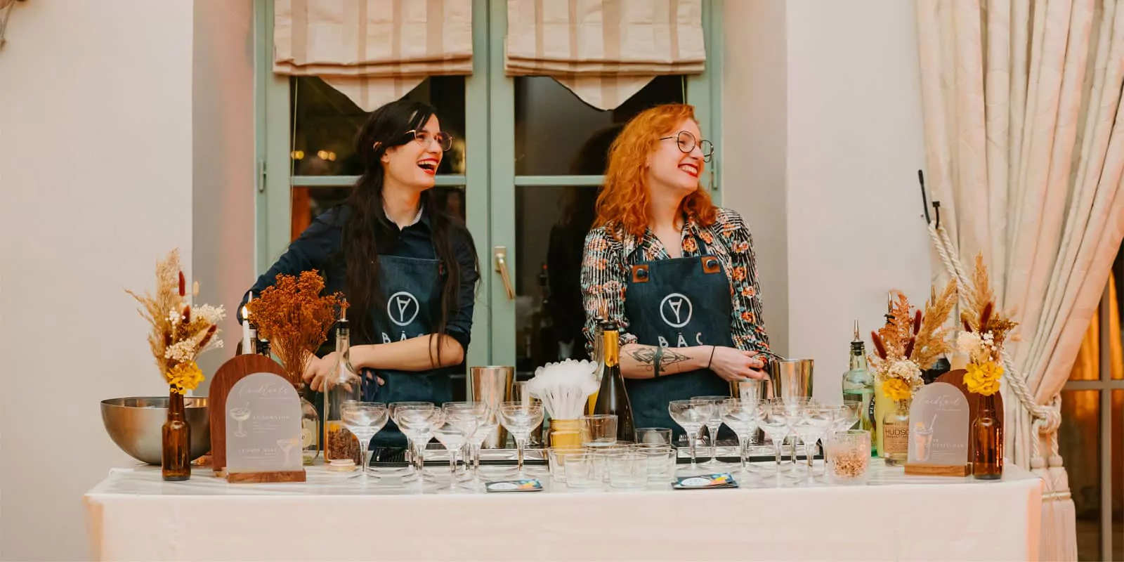 2 barmaids heureuses derrière leur bar à cocktails